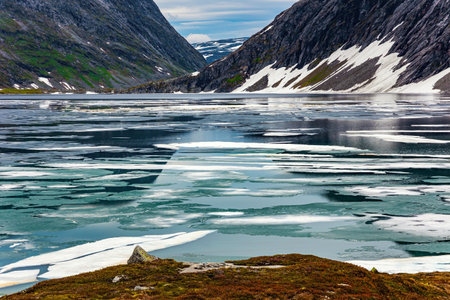 Kingdom of the Snow Queen. Lake Djupvatnet is covered with ice in July. The mountains are covered with freshly fallen snow. Summer trip to Norwayの写真素材