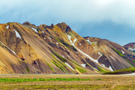 Colored mountains of Landmannalaugar. Travel to exotic Iceland. Remains of last year's snow and hot thermal springs of mineral waterの写真素材