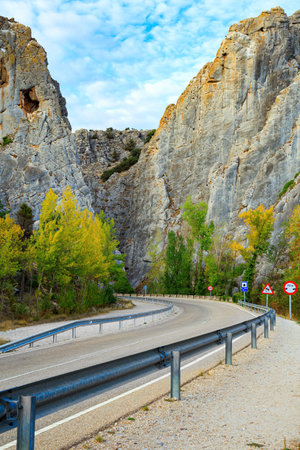 Gray rocks illuminated by sunset. The trip to Spain. Asphalt highway passes among steep cliffs.  The sky is covered with light clouds.の写真素材