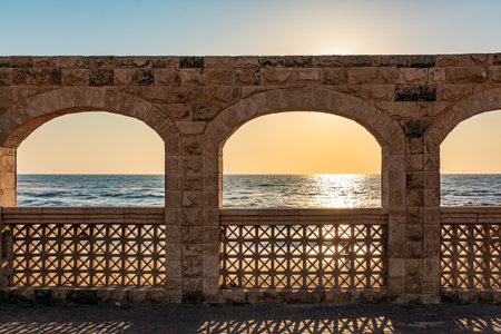 Sunset on the Mediterranean Sea. Picturesque stone arches illuminated by the setting sunの写真素材