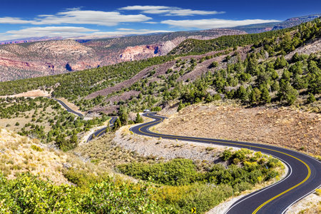 The asphalt surface glistens in the bright sun. Magnificent serpentine of the highway. US. Utah Red Sandstones. Fine autumn dayの写真素材