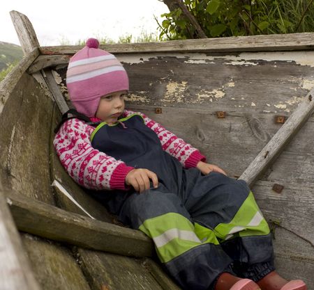 Bored and upset child (3 years old) sitting in an old boat.の写真素材