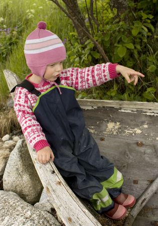 Little girl (3 years old) playing in an old wooden boat, pointing the direction. の写真素材