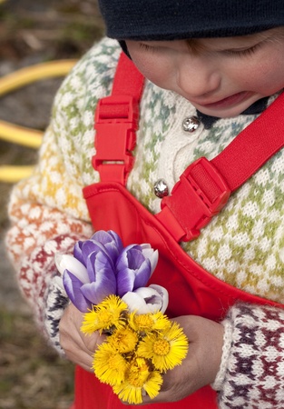 Child holding a bouquet of the first spring flowersの写真素材