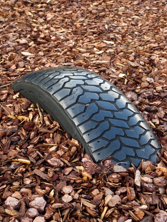 Tire buried in the ground, half covered in brown barkの写真素材
