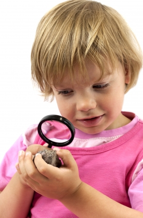 Girl with magnifying glass studying a rockの写真素材