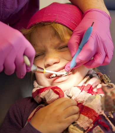 Little girl getting her teeth checked at the dentistの写真素材
