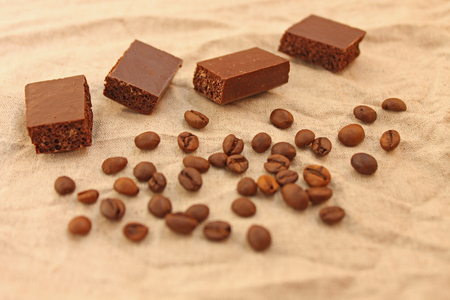 Milk porous chocolate sweets with coffee beans on a linen texture background. Copy space.の写真素材