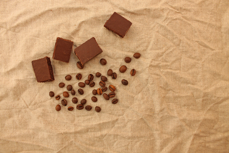 Milk porous chocolate sweets with coffee beans on a linen texture background. Copy space. Flat lay.の写真素材