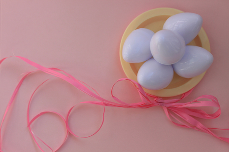 Plastic toys eggs on pink background close up. White Easter egg on pastel background. Kids toys. Happy Easter concept. Minimal concept. Flat lay. Top view.の写真素材