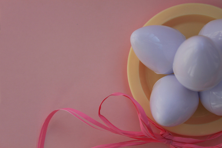 Plastic toys eggs on the plate on pink background close upの写真素材