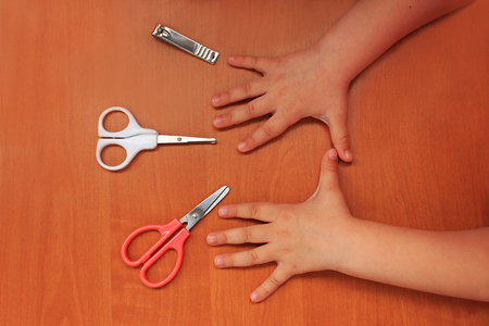 Special scissors for kids with rounded tips and nail clippers. Hand and nail care for the child. Children's manicure. Wooden background. Top view. Flat lay.の写真素材