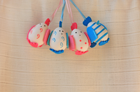 Easter holiday concept with cute handmade eggs, chicks with felt wings, tail and tuft. Funny chickens with stripes and dots. Blue boys eggs and pink girls eggs.の写真素材