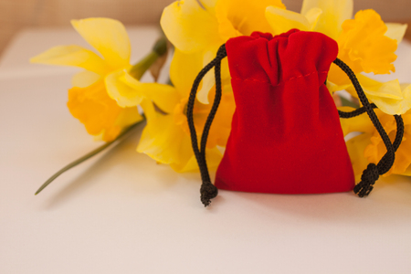 Red velvet pouch with yellow flowers on a white background isolated, copy space. Handbag for wedding rings, marriage proposal, wedding fashion.の写真素材