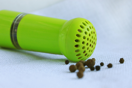 Black peppercorns ans allspice in ancient metal mortar with pestle on linen background. Old home kitchen appliances for grinding spices, nuts, herbs, coffee beans and others.の写真素材
