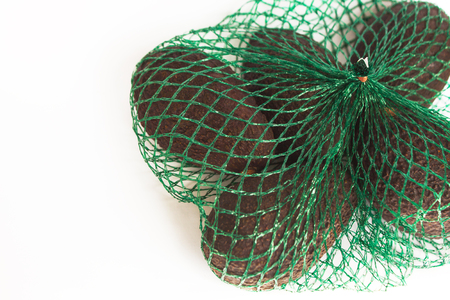 Fresh organic avocados in a green string bag on a white background isolated, healthy food concept, copy space.の写真素材