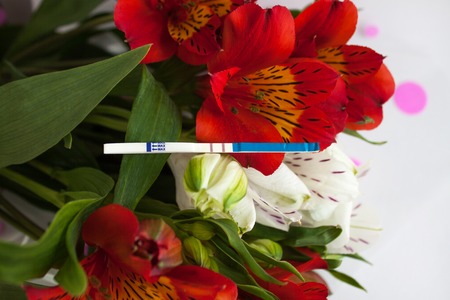 Positive pregnancy test with a bouquet of alstroemeria flowersの写真素材