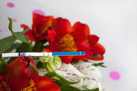 Positive pregnancy test with a bouquet of alstroemeria flowersの写真素材
