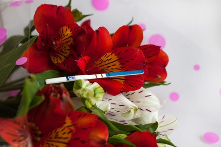 Positive pregnancy test with a bouquet of alstroemeria flowersの写真素材