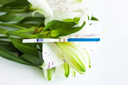 Positive pregnancy test with a bouquet of white alstroemeria flowersの写真素材