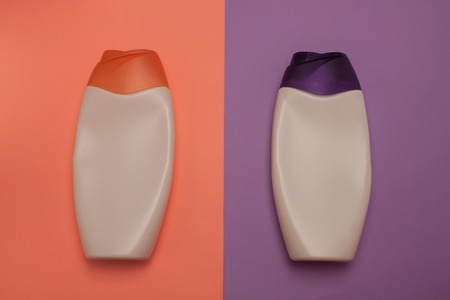 Two cosmetic packaging bottles, containers. Beauty, shower, decorative cosmetics. Peach and purple colors background, flat lay, top view, minimalistic pop-art style.の写真素材
