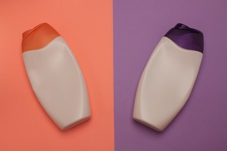 Two cosmetic packaging bottles, containers. Beauty, shower, decorative cosmetics. Peach and purple colors background, flat lay, top view, minimalistic pop-art style.の写真素材