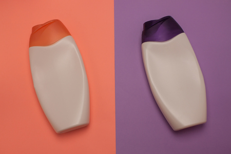 Two cosmetic packaging bottles, containers. Beauty, shower, decorative cosmetics. Peach and purple colors background, flat lay, top view, minimalistic pop-art style.の写真素材