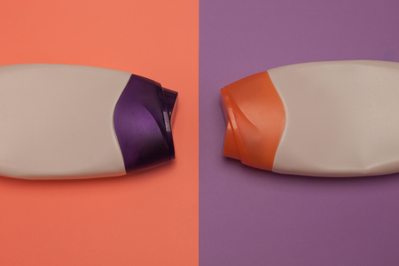 Two packaging bottles of cosmetic products, containers. Beauty, shower, decorative cosmetics. Peach and purple colors background, flat lay, top view, minimalistic pop-art style, branding mock up.の写真素材