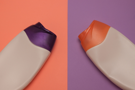Two packaging bottles of cosmetic products, containers. Beauty, shower, decorative cosmetics. Peach and purple colors background, flat lay, top view, minimalistic pop-art style, branding mock up.の写真素材