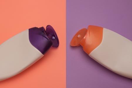 Two opened cosmetic packaging bottles, containers. Beauty products, shower, decorative cosmetics. Peach and purple colors background, flat lay, top view, minimalistic pop-art style, branding mock up.の写真素材