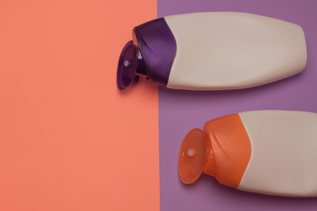 Beauty, decorative cosmetics bottles. Peach and purple colors background, flat lay, top view, minimalistic pop-art styleの写真素材