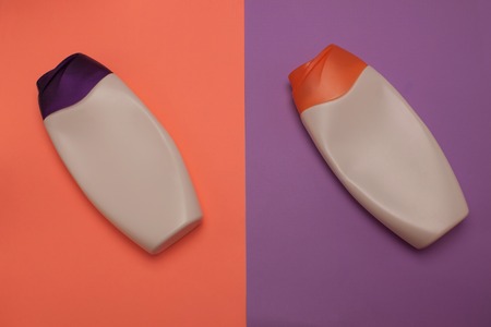Two opened cosmetic packaging bottles, containers. Beauty products, shower, decorative cosmetics. Peach and purple colors background, flat lay, top view, minimalistic pop-art style, branding mock up.の写真素材