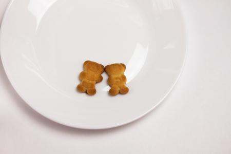 Two cute bears cookies on the ceramic round plate isolated on white background. Breakfast time. Couple of lovers, I love you, declaration of love, forever together. View from above, flat lay.の写真素材