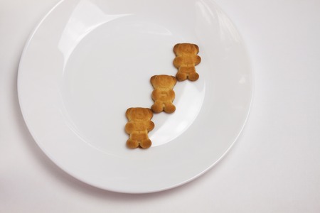 Three cute bears cookies on the ceramic round plate isolated on white background. Breakfast time. Friends, kids party, table settings, celebration. View from above, flat lay.の写真素材