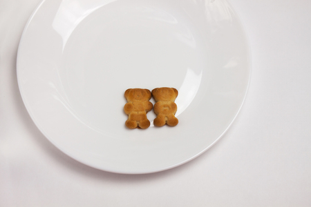 Two cute bears cookies on the ceramic round plate isolated on white background. Breakfast time. Couple of lovers, I love you, declaration of love, forever together. View from above, flat lay.の写真素材