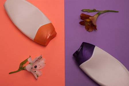 Two bottles of cosmetic products, containers. Beauty, shower, decorative cosmetics. Peach, purple colors background, flat lay,top view,minimalistic pop-art style, branding mock up,alstroemeria flowersの写真素材