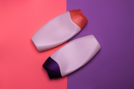 Two packaging bottles of cosmetic products, containers. Beauty, shower, decorative cosmetics. Pink and purple colors background, flat lay, top view, minimalistic pop-art style, branding mock up.の写真素材