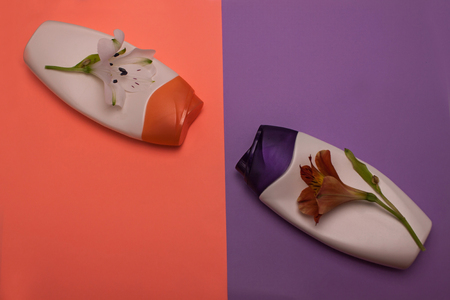 Two bottles of cosmetic products, containers. Beauty, shower, decorative cosmetics. Peach, purple colors background, flat lay,top view,minimalistic pop-art style, branding mock up,alstroemeria flowersの写真素材