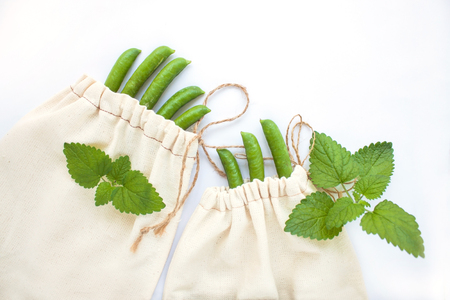 Zero waste concept, reusable cotton bags for free plastic shopping with green peas and fresh greens, save the planet.Vegan,healthy, nutrition, eco style living, copy space, white background, flat lay.の写真素材