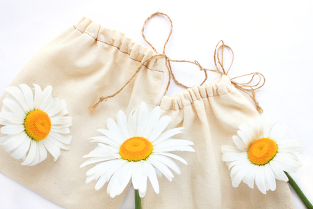 Zero waste concept, reusable hand-made cotton bags for free plastic shopping with chamomiles flowers, save the planet.Vegan,healthy, nutrition, eco style living, copy space, white background, flat layの写真素材