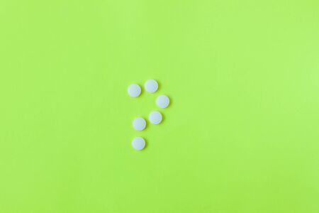 Pills in a shape of question mark on a yellow background. Flat lay, top view, minimalistic style. Vitamins, drugs, dietary supplements.の写真素材