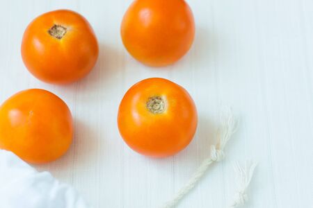 Cotton shopping bag with organic eco yellow tomatoes on white linen background.Caring for the environment, low plastic concept, zero waste,mindful eating. White fabric hand made bag, minimalism.の写真素材