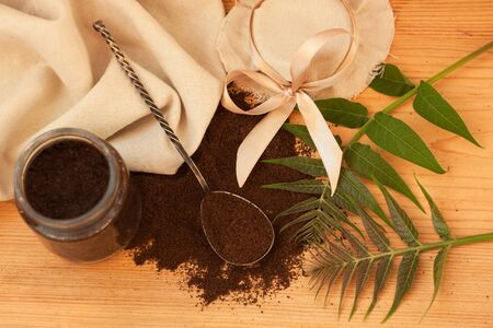 A glass jar of ground coffee with linen fabric and ribbon, an antique spoon, palm brunch. Body scrub, mixed sugar, oil and essentials.Homemade cosmetic,peeling. Flatlay. Wooden background,copy space.の写真素材
