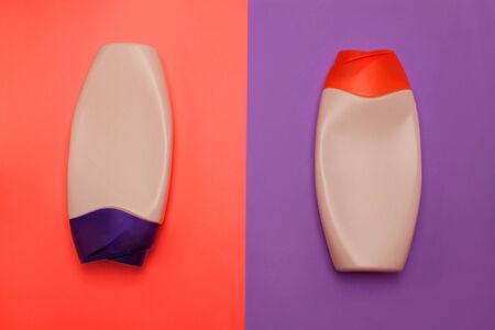 Two packaging bottles of cosmetic products, containers. Beauty, shower, decorative cosmetics. Neon peach and purple colors background, flat lay, top view, minimalistic pop-art style, branding mock up.の写真素材