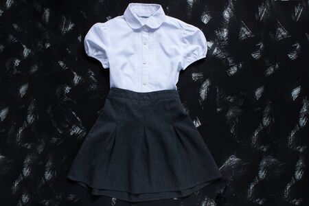 White shirt and grey skirt on black background. Uniform. The first of september, new school year supplies. Back to school banner, education concept. Top view, flatlay, copy space.の写真素材
