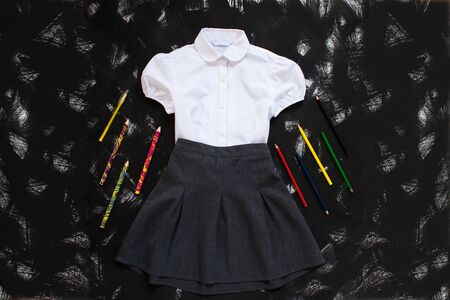 Uniform. White shirt, grey skirt and stationery on black background. The first of september, new school year supplies. Back to school banner, education concept. Top view, flatlay, copy space.の写真素材