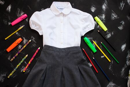 Uniform. White shirt, grey skirt and stationery on black background. The first of september, new school year supplies. Back to school banner, education concept. Top view, flatlay, copy space.の写真素材
