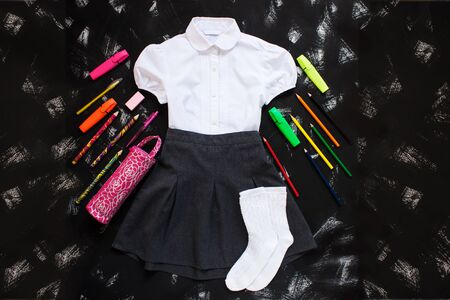 White shirt, grey skirt, white socks and stationery on black background. Uniform. The first of september, new school year supplies. Back to school banner, education concept.Top view,flatlay,copy spaceの写真素材