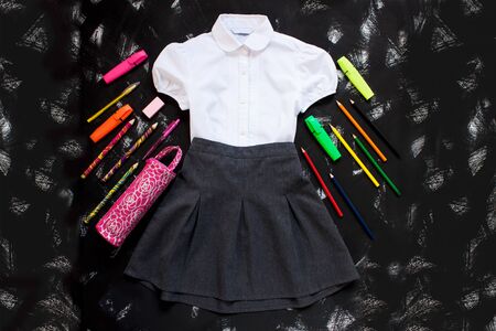 Uniform. White shirt, grey skirt and stationery on black background. The first of september, new school year supplies. Back to school banner, education concept. Top view, flatlay, copy space.の写真素材