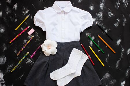 White shirt, grey skirt, white socks and stationery on black background. Uniform. The first of september, new school year supplies. Back to school banner, education concept.Top view,flatlay,copy spaceの写真素材